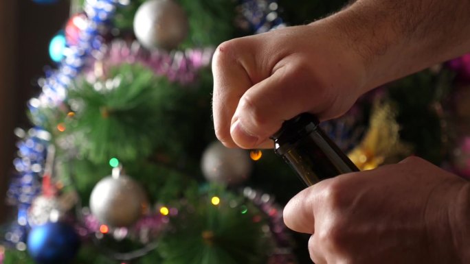 在装饰着闪闪发光的花环的圣诞树的背景下，一瓶香槟正在被打开。