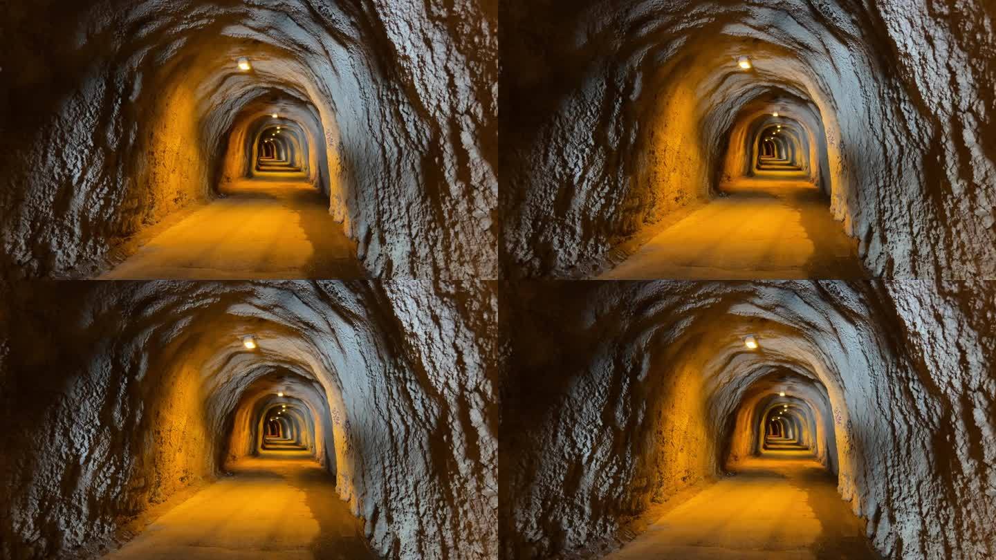 山上有一条石崖隧道。洞穴隧道灯光和凹凸不平的墙壁。高品质4k画面