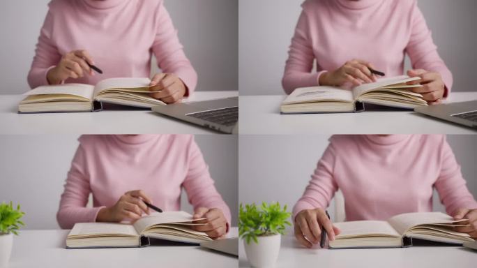 女性手握笔翻页的特写。女人在看书。