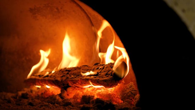 在烧木头的石炉里燃烧的火的特写。餐厅里的披萨烤箱。壁炉