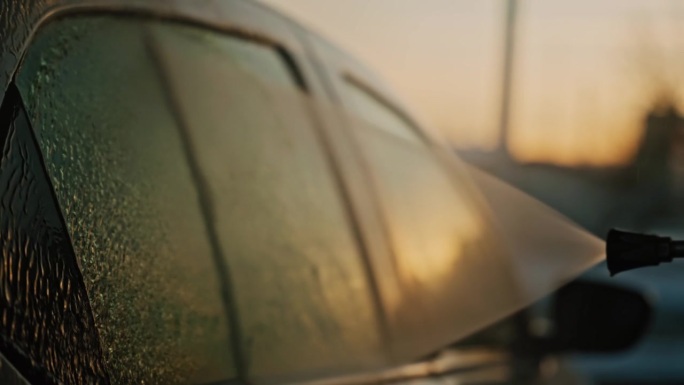 日落时分，户外自助洗车站高压水枪洗车车窗特写