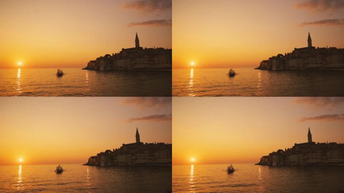 日落时以老城为背景的船在海上航行的慢镜头镜头。罗维尼，伊斯特拉，克罗地亚。