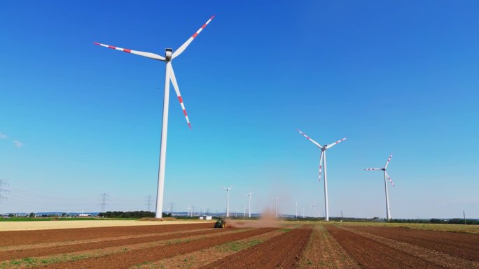 空中和谐运动:风力涡轮机和农民耕种田地从地面水平视图