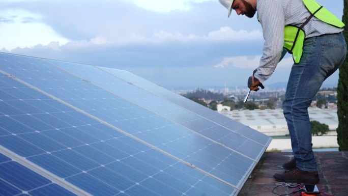 安装和维护太阳能电池板的工程师，可再生能源发电的概念，在蓝天背景下屋顶工作的专业技术人员;影印空间摄