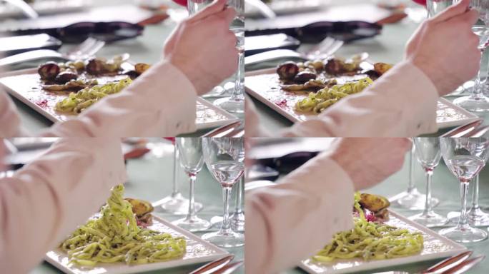 美味的传统意大利自制宽面条配上新鲜的罗勒酱，白色盘子配上小菜，用手旋转叉子品尝意大利美食，在餐厅享用