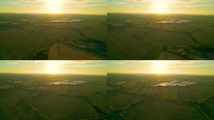航拍，镜头光晕:飞向冉冉升起的太阳，飞越风景优美的英国乡村