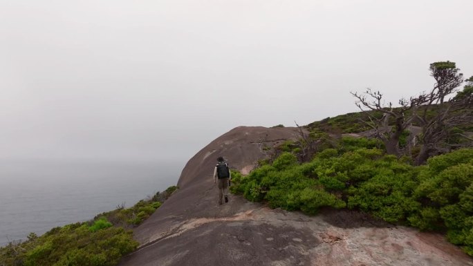 一名男子走上花岗岩板块，走向南大洋半岛的边缘。