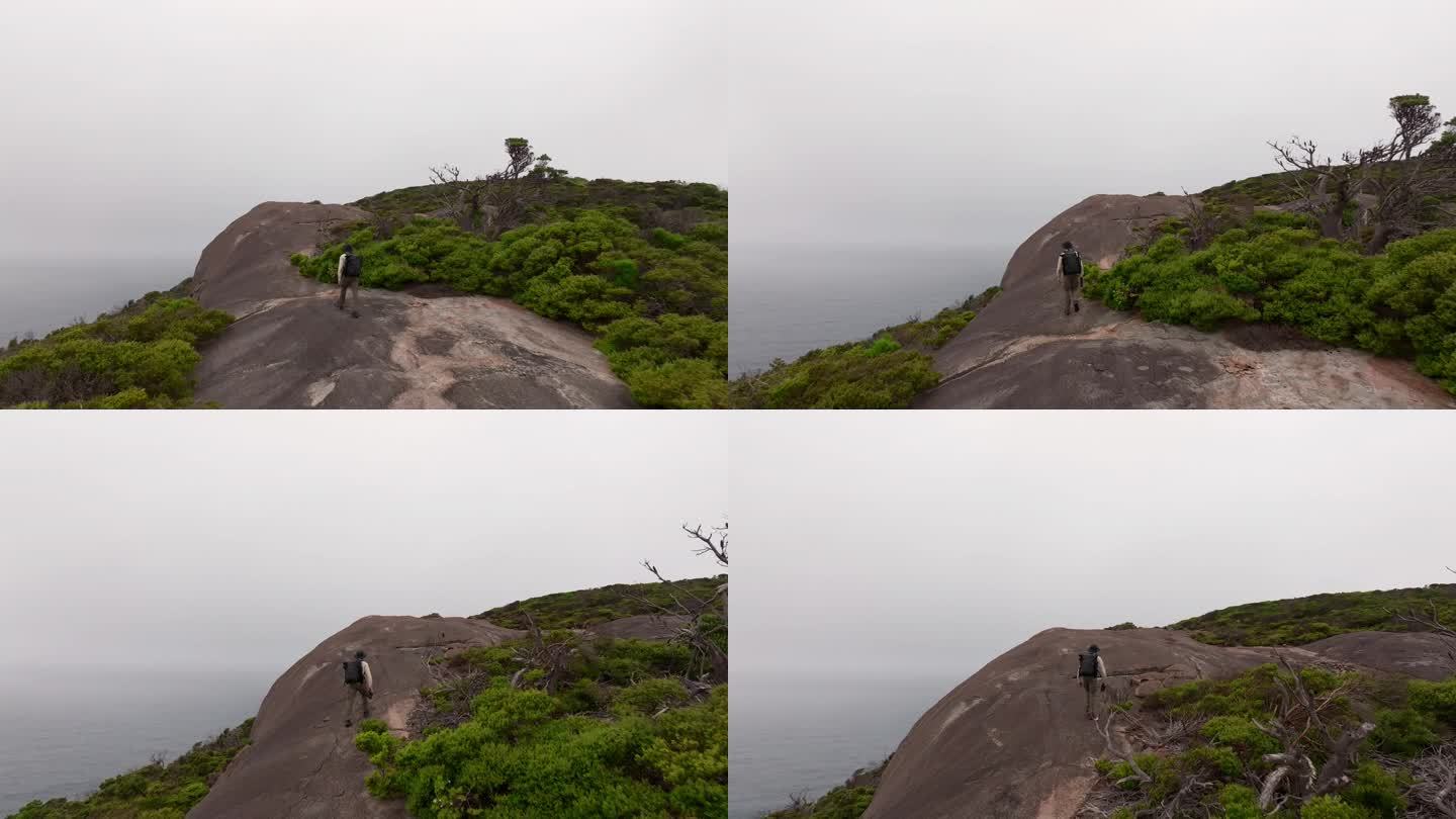 一名男子走上花岗岩板块，走向南大洋半岛的边缘。