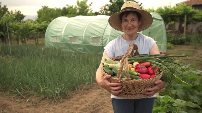 一位年长的妇女提着一篮子沉重的蔬菜