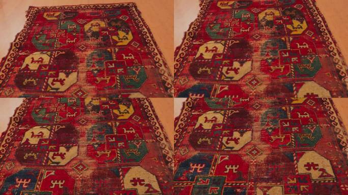 一张由撒马尔罕大师使用古老技术制作的破旧的手工地毯的特写镜头。它布满了民族图案和装饰品。