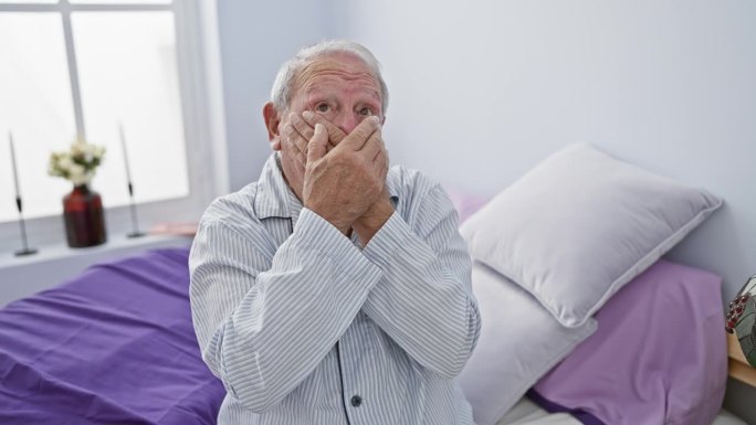 穿着睡衣的老人坐在卧室的床上，惊讶地用手捂住嘴，在室内发现了一个秘密的错误