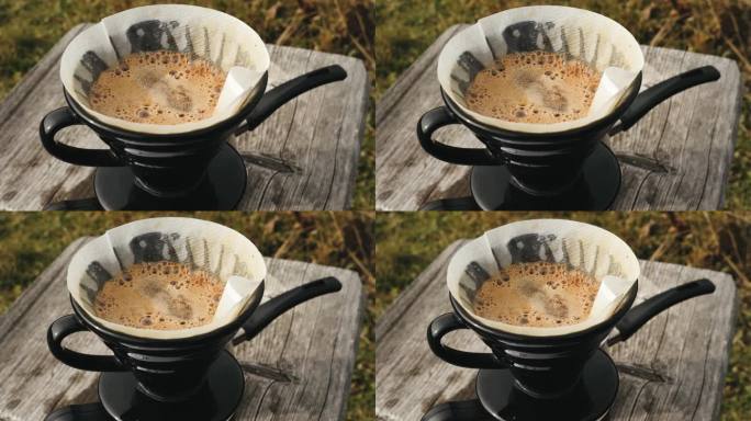 旅行者制作过滤咖啡，把水倒在磨碎的咖啡豆里，对着山景