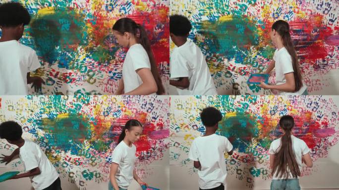年轻可爱的学生用手画彩色的染色墙。启迪