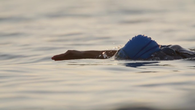 在日落时在海洋中游泳的度假女子的SLO镜头