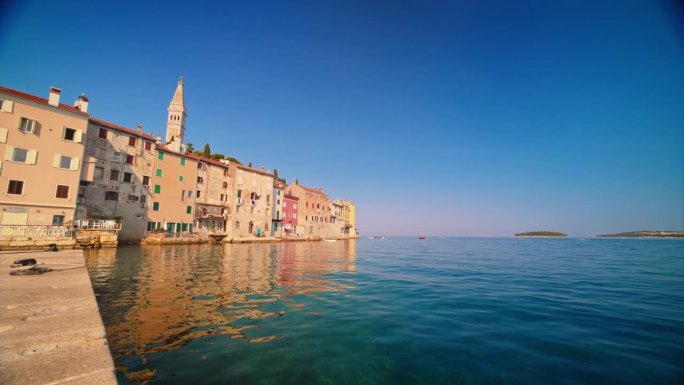 在罗维尼的阳光明媚的日子里，宁静的大海和蓝天衬托下的历史小镇的慢镜头镜头。Istra,克罗地亚。