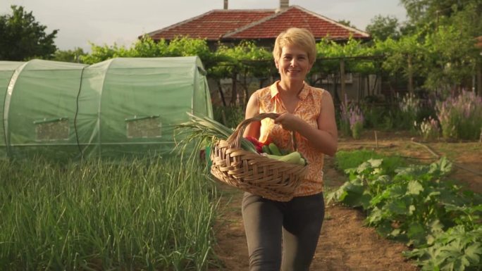 一位兴高采烈的女士提着一篮子新鲜蔬菜走向镜头