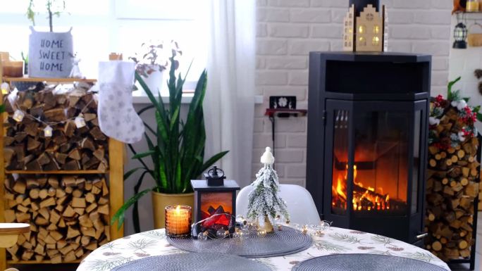 金属黑色的炉子，白色的燃烧壁炉，房子的节日内部装饰为圣诞节和新年，圣诞树。柴堆里的柴火，温馨温暖的家