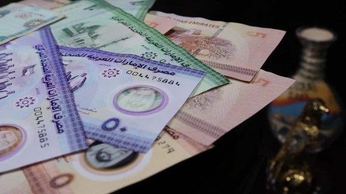 阿联酋迪拉姆纸币在自动桌子上旋转，背景是民族手工艺品和阿拉伯文化的象征。