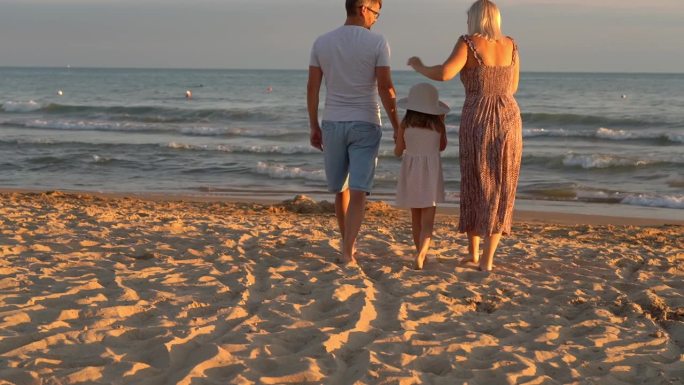 日落时分，一家人在海边的沙滩上散步。暑假，旅游，旅游