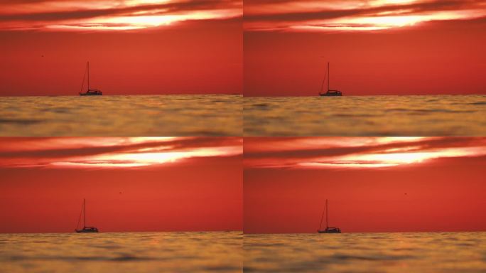 在日落时，地平线上的船与橙色天空的田田诗般的海景