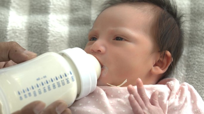 新生儿的脸从奶瓶里喝牛奶新生儿躺在床上喝牛奶妈妈给她的宝宝喂奶可爱的婴儿宝宝在家里用爱喂奶新生儿概念