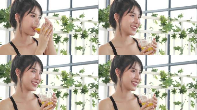 亚洲女性笑着笑着看镜头保健居家健身生活方式。美女饮用新鲜牛奶，低脂，无乳糖。女人的手拿着白色的玻璃杯