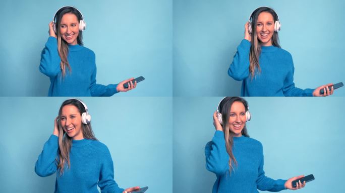 快乐的年轻女子用耳机和智能手机在蓝色背景下听音乐