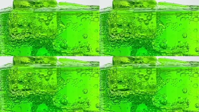 近距离倒软饮料，绿色苏打泡沫与冰到玻璃隔离