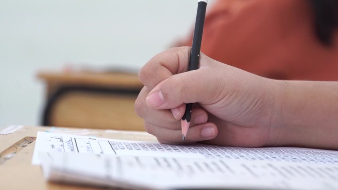 亚洲学生在课堂上使用橡皮擦书写学习考试。在高中的教育。学校学生的阅读笔记，评估在同学入学答卷上的写作