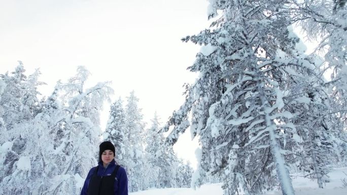 女孩走在雪景中，欣赏芬兰拉普兰的美丽和树木，北极圈