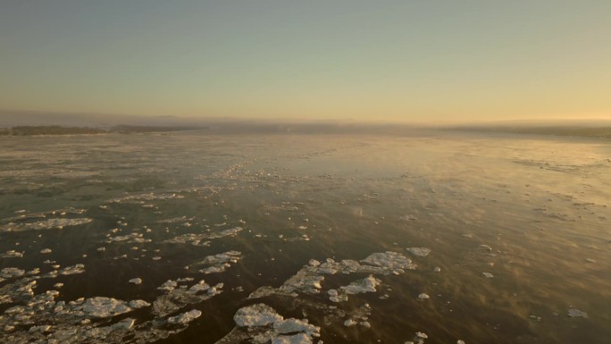 向后鸟瞰冰冻的圣劳伦斯海道，在一个非常寒冷的冬季早晨，日出时