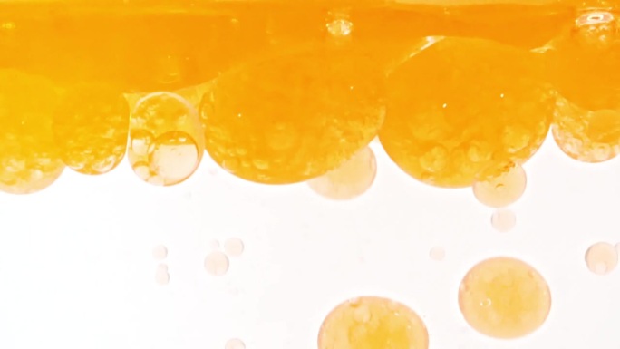 慢动作移动的金黄油，气泡在水中上升在浅白色的背景。带有气泡的透明化妆品凝胶液。宏Shot.v