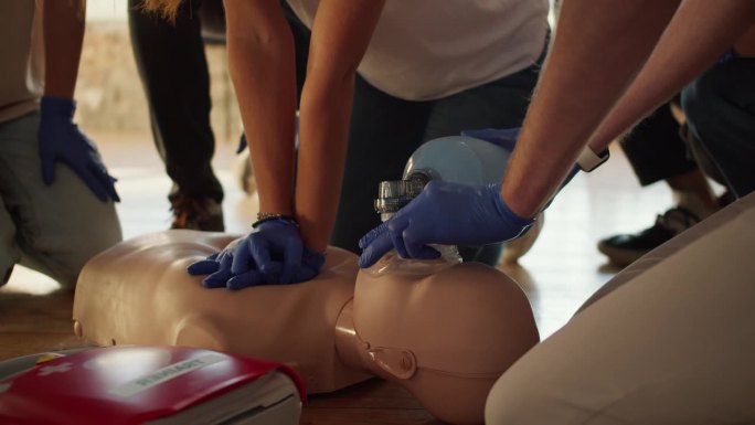 特写镜头:两个人在人体模型和急救袋的帮助下进行心肺复苏术。实际培训。急救培训