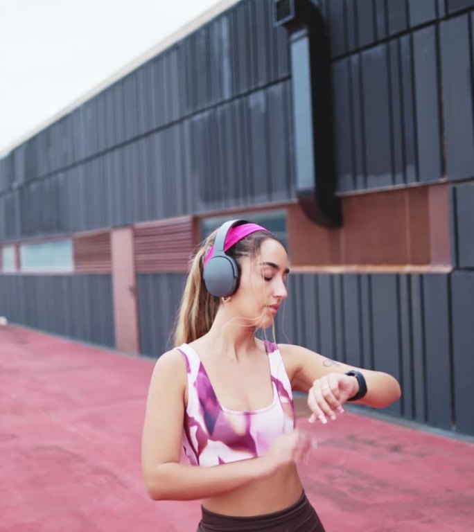 一个年轻女运动员在智能手表上检查健身进度的垂直视频。