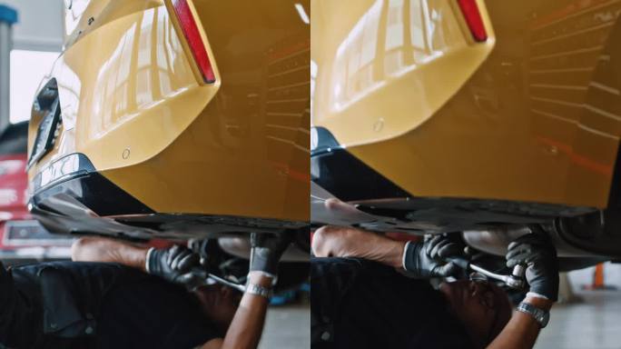 男机械师在汽车修理厂的车下工作