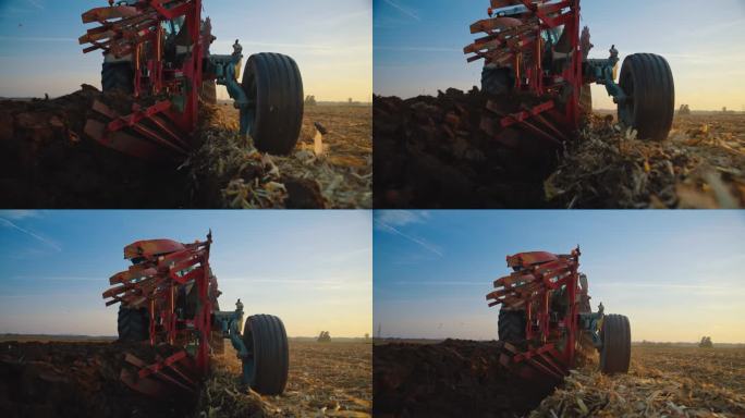 在日落时分，拖拉机对着天空犁着农田