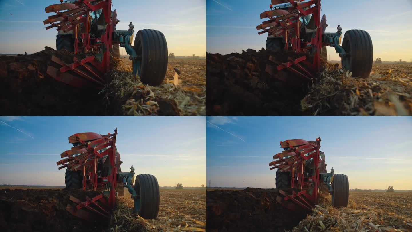 在日落时分，拖拉机对着天空犁着农田