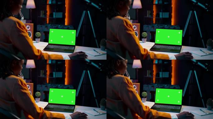 年轻女子在她的家庭办公室使用带有孤立绿屏显示的笔记本电脑