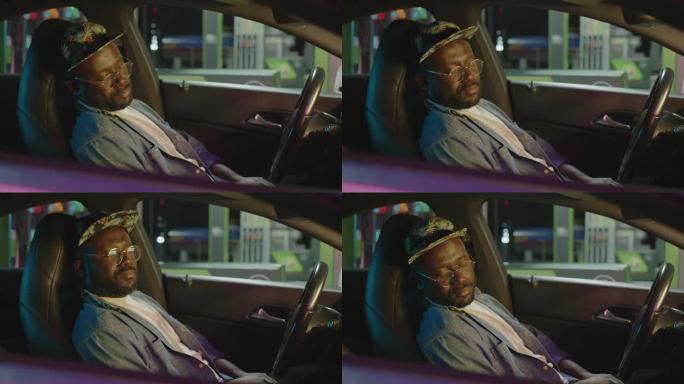 年轻的黑人司机睡在加油站的车里
