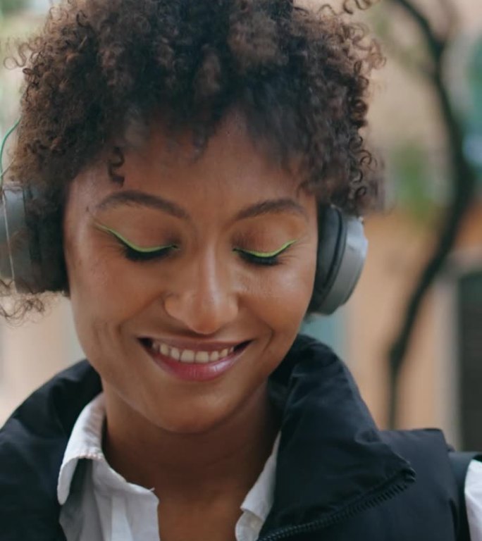 非洲妇女在街道上戴着无线耳机欣赏歌曲