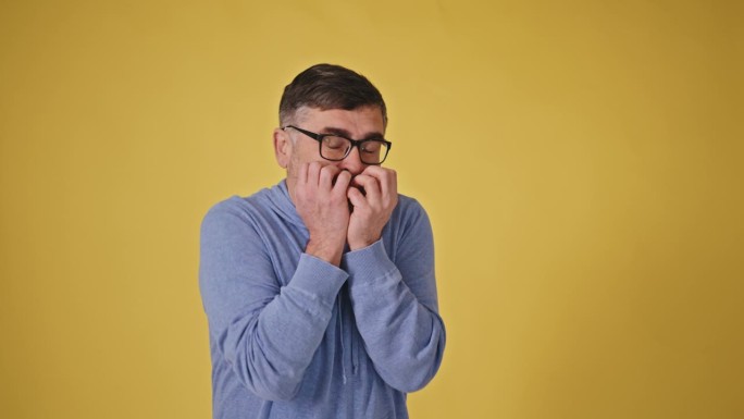 一位戴着黄色背景眼镜的惊慌失措的老人，双手颤抖着，害怕地从镜头前转过身来