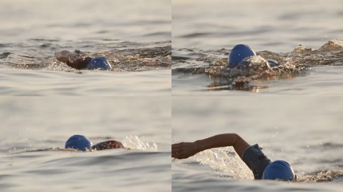 日落时分，戴着帽子在海洋中游泳的活跃女性的慢镜头镜头。一个女人正在海里游泳。