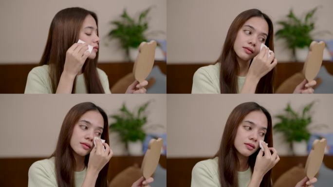 亚洲女性坐着照镜子，手捧纸巾，吸走脸上的油脂，减少污垢的产生，慢慢吸收增稠，以防止面部皮肤受到刺激。