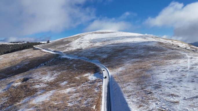 在一个阳光明媚的日子里，鸟瞰白雪覆盖的高原，道路被剩余的雪变白了