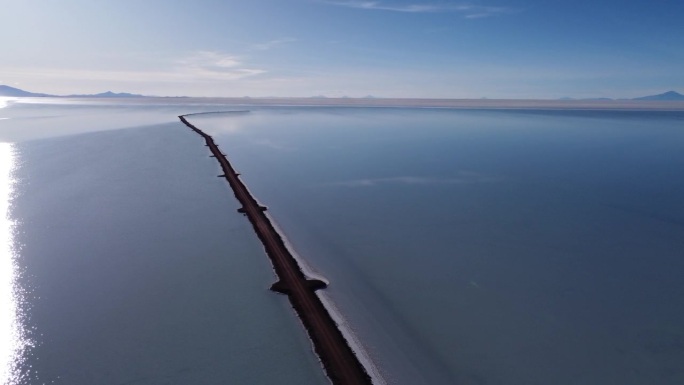 航拍:玻利维亚乌尤尼，狭窄的道路延伸到广阔的浅盐湖