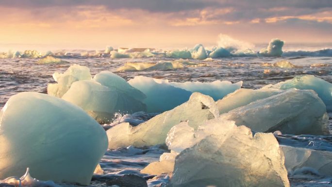 在黄金时段，冰山在黑色的海滩上闪耀，冰岛钻石海滩上的日出，受欢迎的旅游景点，清澈的冰被海浪撞碎，气候