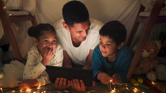 晚上，父亲和孩子们用平板电脑，流媒体电影和幸福与纽带，家庭和爱在一起。晚上，男家长和孩子们玩科技，玩