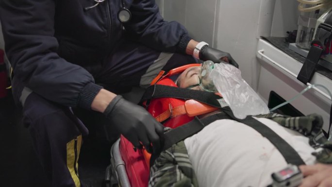 病人、医生和急救人员在救护车上戴着氧气面罩、受伤或戴着颈托。急救中心，911和麻醉人员进行医疗保健，