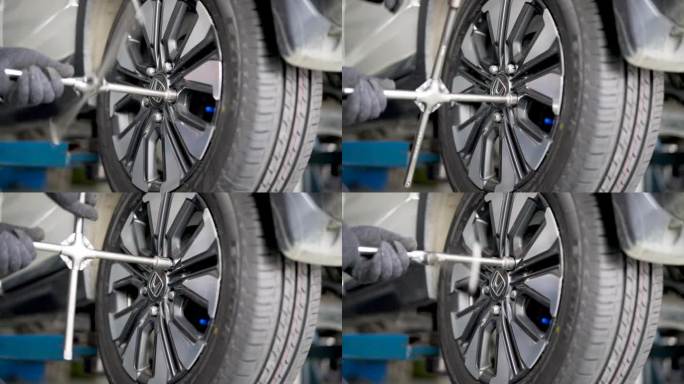 汽车修理工用十字扳手把钻好的车轮上的车轮螺母拧紧。轮胎有洞。换轮胎。