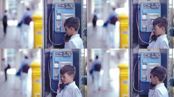 男孩在城市景观中接听公共电话